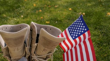 Rüzgarda sallanan bir Amerikan bayrağının sembolü olarak evine dönen bir Amerikan askerinin çizmeleri.