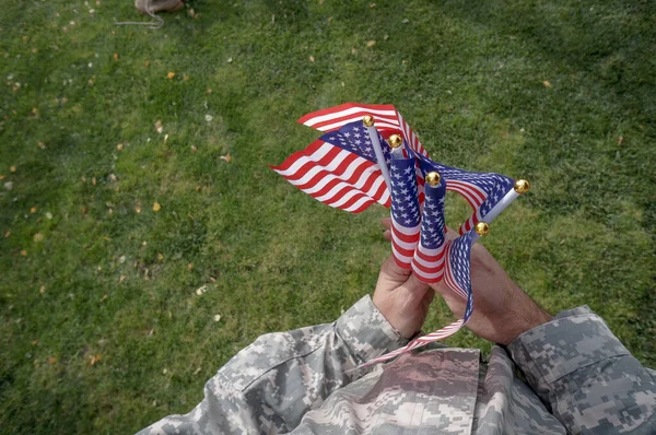 アメリカ兵は休暇で公園の緑の芝生の上で風になびく両手旗を持っている ストック画像