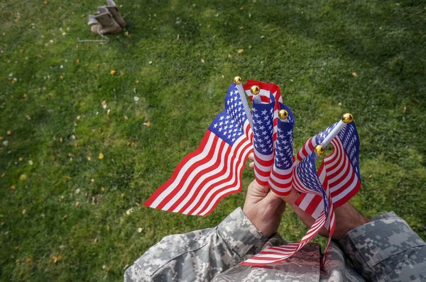 アメリカ兵は休暇で公園の緑の芝生の上で風になびく両手旗を持っている ストックフォト