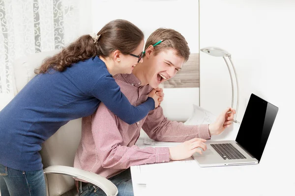 Casal jovem rindo alto atrás do computador portátil no escritório — Fotografia de Stock