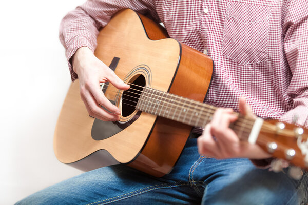 Shot of man in shirt and jeans playing on classic guitar