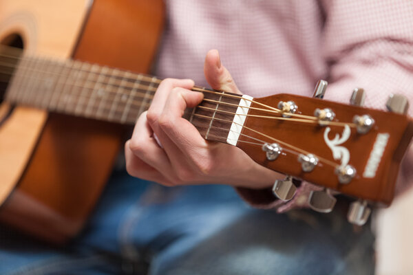 Men playing on classic wooden guitar