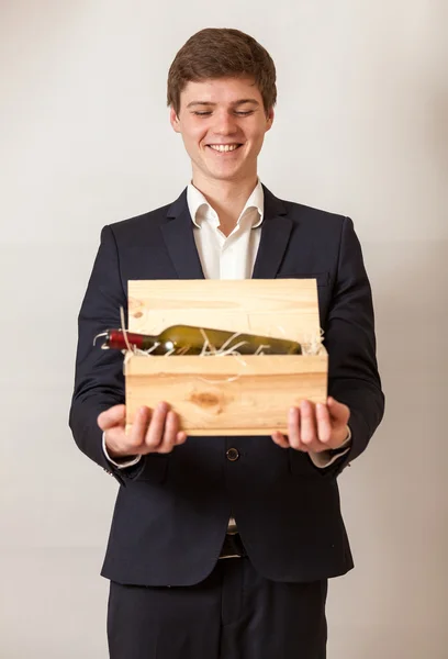 Elegante uomo sorridente e che trasporta scatola di legno con vino rosso — Foto Stock