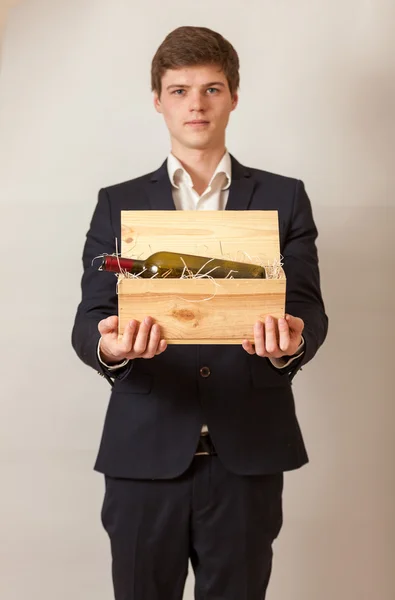 Elegante uomo in abito nero contenente scatola di legno con vino — Foto Stock