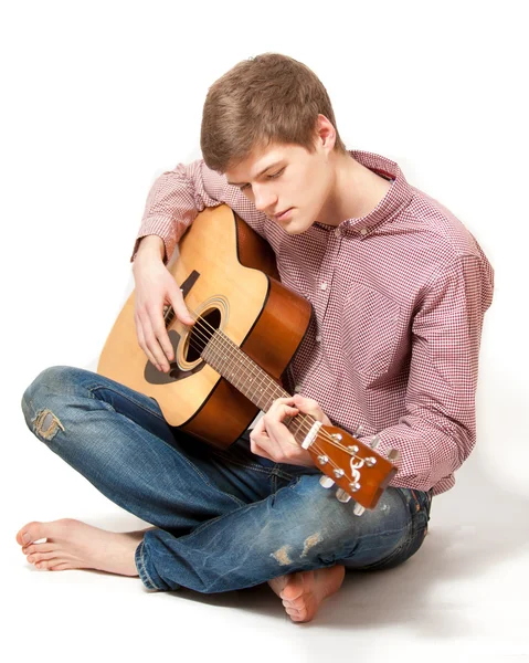 人の床に座っておよび古典的なギターで演奏 ストックフォト