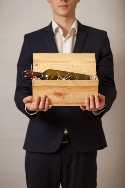 Elegante uomo in giacca e cravatta contenente scatola di legno con vino Immagine Stock