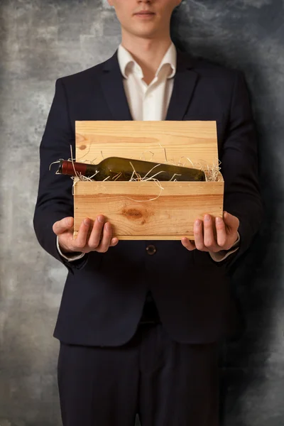 Élégant homme tenant boîte avec du vin contre le mur de béton Photos De Stock Libres De Droits
