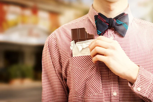 Человек, вытаскивающий шоколад из кармана на улице Лицензионные Стоковые Фото