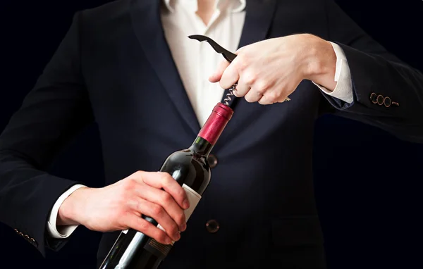 Foto dell'uomo che apre una bottiglia di vino con cavatappi Immagini Stock Royalty Free