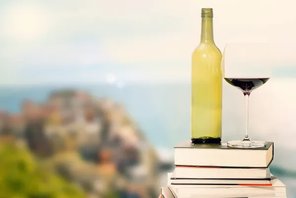 Bouteille de vin et verre sur les livres contre la vue sur la mer Images De Stock Libres De Droits