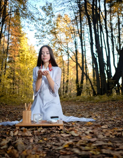Dziewczyna w niebieskim kimono siedzi w jesiennym lesie i przygotowuje herbatę Obraz Stockowy