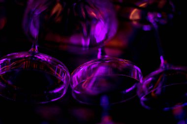 Bir bardak kokteyl. Bardaklar restoranda barın üstünde asılı. Şarap için boş bardaklar. Restorandaki barın üstündeki rafta kokteyl bardakları var. mavi ışıklar, mavi arkaplan, gece