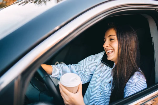 Young Woman driving car with coffee in her hand