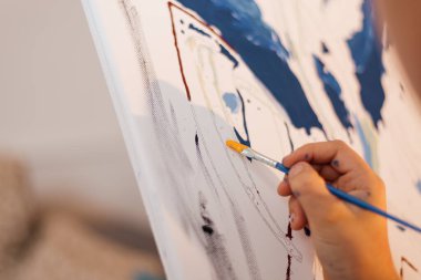 Bir çocuk boyalı ve fırça renginde bir resim çiziyor.