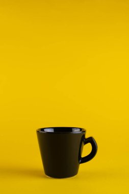 Siyah bir kupa, sarı bir arka plan. Minimalizm kupası