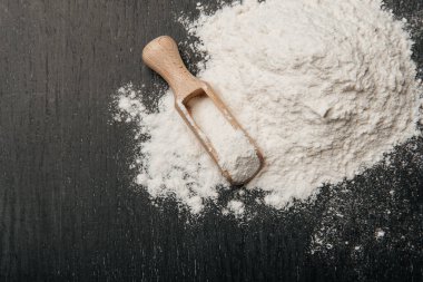 Siyah zemin üzerinde un olan tahta kaşık..