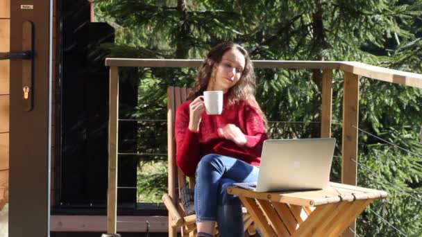 Dziewczyna Rozmawiająca Przez Połączenie Wideo Laptopie Siedząc Drewnianym Krześle Tarasie — Wideo stockowe