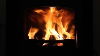 Kızgın bir ateşte yakılacak odun. Ocakta, şöminede parlak bir alevin yakın görüntüsü. Gece vakti şöminede turuncu-sarı ateş dilleri. Soyut video görüntüleri. Sıcak ev atmosferi.