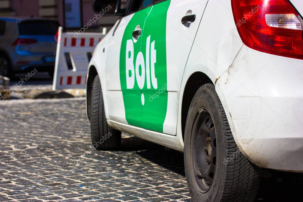 Kyiv, Ukraine. May 3, 2021. White sedan car with green logo of Bolt cab service is driving down a paved city street. A popular transportation network company from Tallinn, Estonia. Online city taxi.