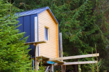 Gündüz vakti çam ormanlarındaki modern kır evi. Yeşil ormandaki sandviç panellerinden yapılmış modern bir yapı. Yeni modüler ev dış görünüşü. Modüler biçim mimarisi 