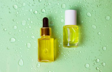 Konteynırlar, kozmetik için ambalajlar. Cam şişe pipeti damlatıcısı yüz için gerekli yağ, arka planda yeşil su damlaları. Kozmetik ürünleri. Doğal ekolojik masaj yağı. Kütikül nemlendirici için yağ