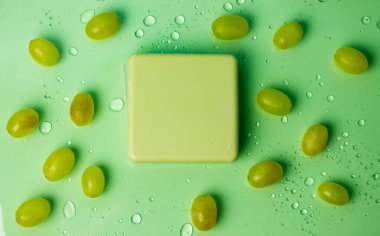 Su damlaları üzerinde yeşil üzümler arasında el yapımı sabun. Eko Kozmetik.