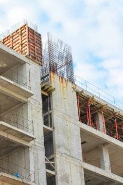 Yüksek katlı yeni bir apartmanın beton inşaatı. Tamamlanmamış binaların dış görünüşü. Yerleşik kompleks dış görünüş. Gayrimenkul. Levhalar, duvarlar, metal çubuklar. Dikey fotoğrafçılık