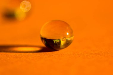 Altın renkli balık yağı hapı, tablet, omega 3 jelatin kapsül yakın plan portakal masasında zıt uzun gölgeler bırakır. Tıbbi, sağlık, ilaç tedavisi, minimal monokrom geçmişi.