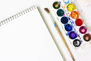 Çizim defterini açtım, masanın üzerinde suluboya renkler var. Çizim dersi.