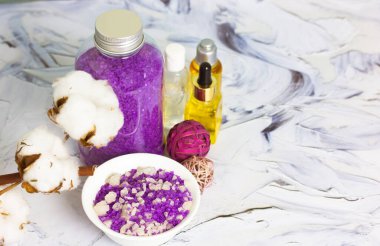 İçinde mor lavanta tuzu kavanozu, pamuk çiçeği, siyah beyaz fırça darbeleri üzerine serum yağı şişeleri olan kompozisyon. Spa işlemleri ve vücut bakımı için güzellik ürünleri. Banyo tedavileri