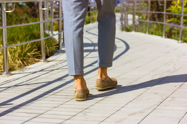 Feet of pedestrian businessman. Man in gray pants, brown shoes walking on big city street at sunny day. Business, leisure lifestyle concept. Contrasting shadow on a ground. Moving, strolling, stepping — Stock Photo, Image