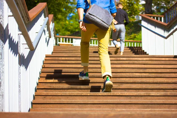 Businessman freelancer, student. Man guy in casual style runs up wooden steps of staircase in hurry to run errands. Big city resident with large crossbody bag, portfolio running up. People on a street — Foto Stock