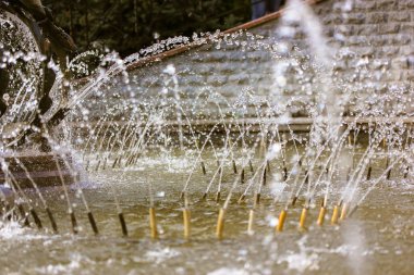 Şehir parkındaki çeşmeye su sıçratmak. Jetlerden uçan damlalar.