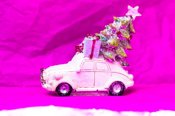 Carro de brinquedo, presentes de árvore de Natal no telhado em um fundo rosa. Feliz Ano Novo 2022. — Fotografia de Stock