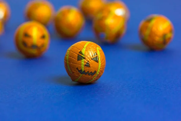 Jack o lantern pumpkins in a form of decorative beads or balls scattered on minimalistic blue background with copy space. Sweets, candies, trick-or-treats. Halloween celebration Oct. 31. Party treats. — Stock Photo, Image