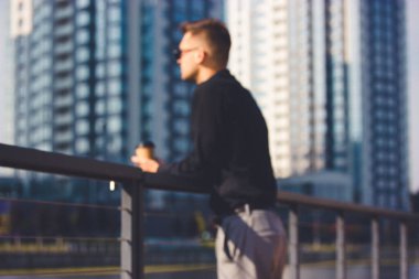 Bulanık, tanınmayan işadamı, çok katlı binalara karşı iskelede duruyor..