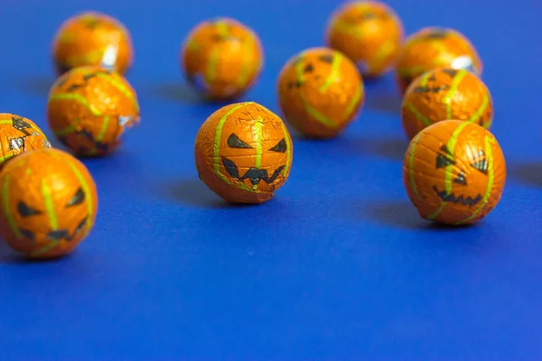 Jack o lanterne citrouilles dans une forme de perles décoratives ou des boules dispersées sur fond bleu minimaliste avec espace de copie. Des bonbons, des bonbons, des bonbons. Célébration d'Halloween 31 octobre. Gâteries de fête. Images De Stock Libres De Droits