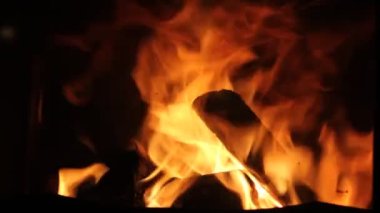 Kızgın bir ateşte yakılacak odun. Ocakta, şöminede parlak bir alevin yakın görüntüsü. Gece vakti şöminede turuncu-sarı ateş dilleri. Soyut video görüntüleri. Sıcak ev atmosferi.