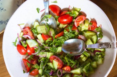 Taze bitkilerden oluşan sebze salatası, dilimlenmiş domates, salatalık, üzerine beyaz bir kâse manzarası olan doğal zeytin yağıyla tatlandırılmış. Düzgün ve sağlıklı bir ev yapımı yemek. Kırsal basit yiyecekler.