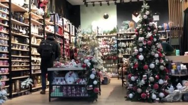 Kyiv, Ukrayna, 4 Aralık 2021. Müşteriler 2022 yılbaşı arifesinde hediye seçmek için dekor dükkanına giderler. Noel ağacında toplarla, oyuncaklarla parıldayan çelenk ışıkları. Aralık 'ta alışveriş merkezinde.