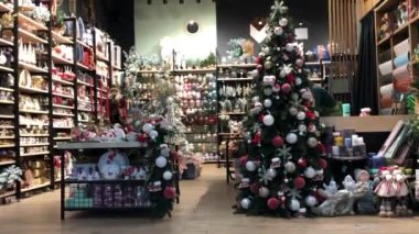 Kyiv, Ukrayna, 4 Aralık 2021. Müşteriler 2022 yılına hediye seçmek için dekor dükkanına giderler. Noel ağacında toplarla, oyuncaklarla parıldayan çelenk ışıkları. Aralık ayında alışveriş merkezinden alışveriş