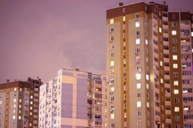 Kiev, Ukrayna. 1 Aralık 2021. Yüksek panelli ve tuğlalı çok katlı binalar akşam gökyüzünün arka planında duruyor. Bir yerleşim alanı, bir sıra, bir bölge. Pencerelerde ışık