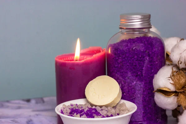 紫丁香海盐洗浴在瓶子里 一支燃烧的蜡烛和一枝棉花花 香皂一块肥皂或干洗发水面部和身体护理 温泉治疗的概念 化妆品 复制空间 — 图库照片