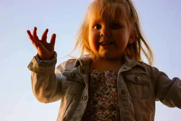 소녀가 카메라 앞에서 흔들며 아동기 컨셉이야 꼬마야 밖에서 하늘을 등지며 — 스톡 사진