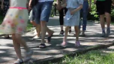 Güneşli yaz günlerinde şehir parkında yürüyen tanınmamış insanlar. Farklı insanların ayakları yeşil çimlerle kaplı bahçede fayanslı bir patikada geziniyor. Doğada, bir sokakta dinleniyor.. 