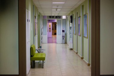 Kyiv, Ukrayna. 1 Haziran 2020. Uzun, boş bir hastane koridorunda bekleyen hastalar için yeşil bir kanepe. Beyaz kapıları olan modern bir tıbbi tesisin koridoru. Kapalı alanda yapay ışıklandırma. İç mekan