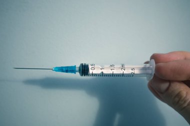2,5 ml şırınga. Kadının elinde steril. Mavi arka planda. Sağlık, ilaç, salgın sırasında aşı, koronavirüs, grip, diğer hastalıklar konsepti. İlaç..