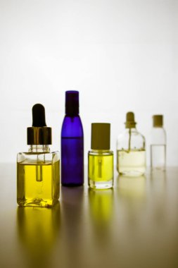 Doğal kozmetik ürünleri olan küçük sarı ve mavi şişelerden oluşan siluetler, temel yağ, beyaz arka planda vücut bakımı aromalı yağlar. Sağlık, spa kompozisyonu. Çeşitli yetenekler, yumuşak cam eşyalar..