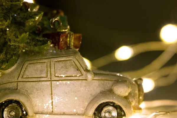 Mały mini zabawka retro samochód z wiecznie zielonym drzewem na dachu i pudełko z kokardą stoi pośród splątanych doprowadziły girlandy z świecącymi światłami. Szczęśliwego Nowego Roku 2022, Wesołych Świąt. Sprzedaż zimowa, zakupy. — Zdjęcie stockowe