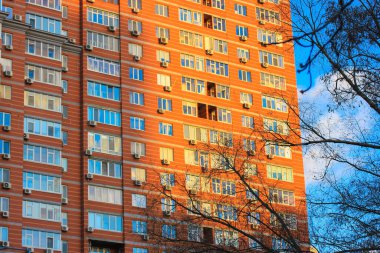 Kiev, Ukrayna, 2 Ocak 2022. Sonbaharda, kışın mavi gökyüzüne karşı yüksek katlı kırmızı tuğlalı apartman duvarı. Pencereleri ve balkonları olan modern bir ev cephesi. Şehir mimarisi.